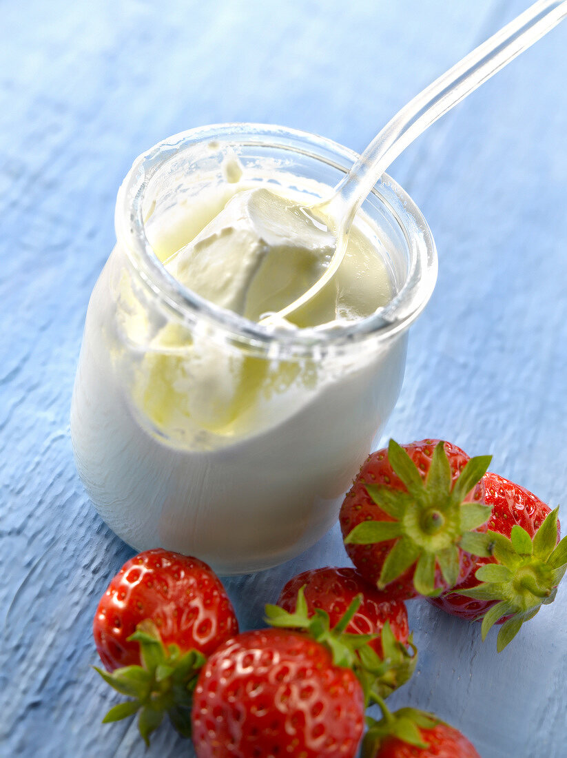 Open yoghurt in a glass pot and strawberries
