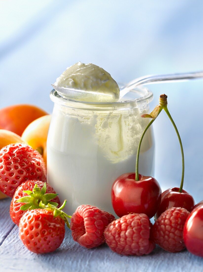 Joghurt im Glas mit Löffel, dazu frisches Obst