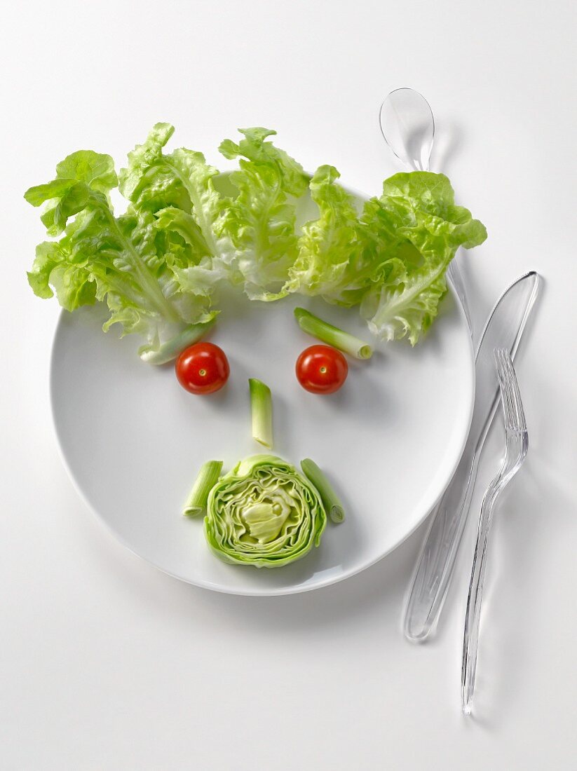 Gesicht aus Salat auf Teller