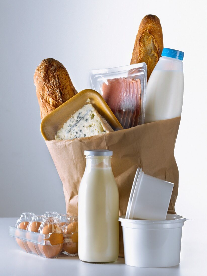 Einkaufstüte mit verschiedenen Lebensmitteln: Baguette, Milch, Käse, Speck und Eier