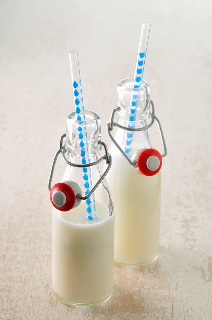 Glass bottles of milk with straws