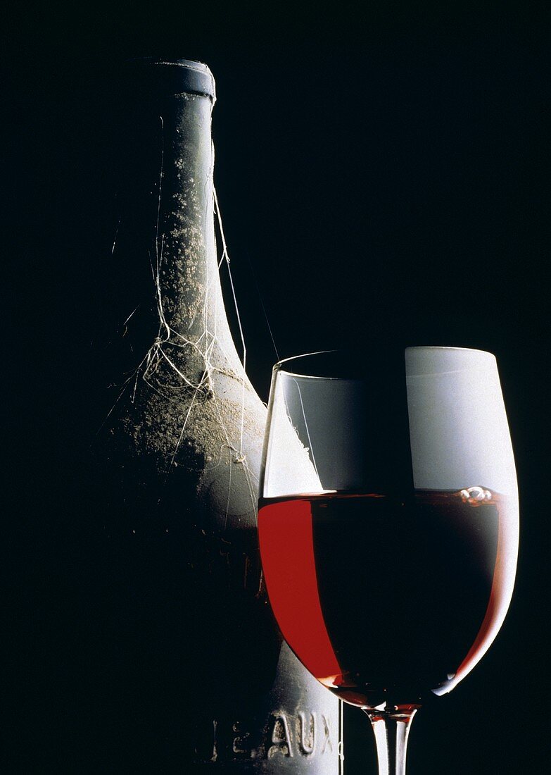Glass of Red Wine with Aged Bottle; Cobwebs