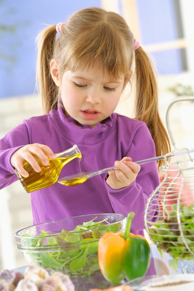 Kleines Mädchen rührt Salatdressing an