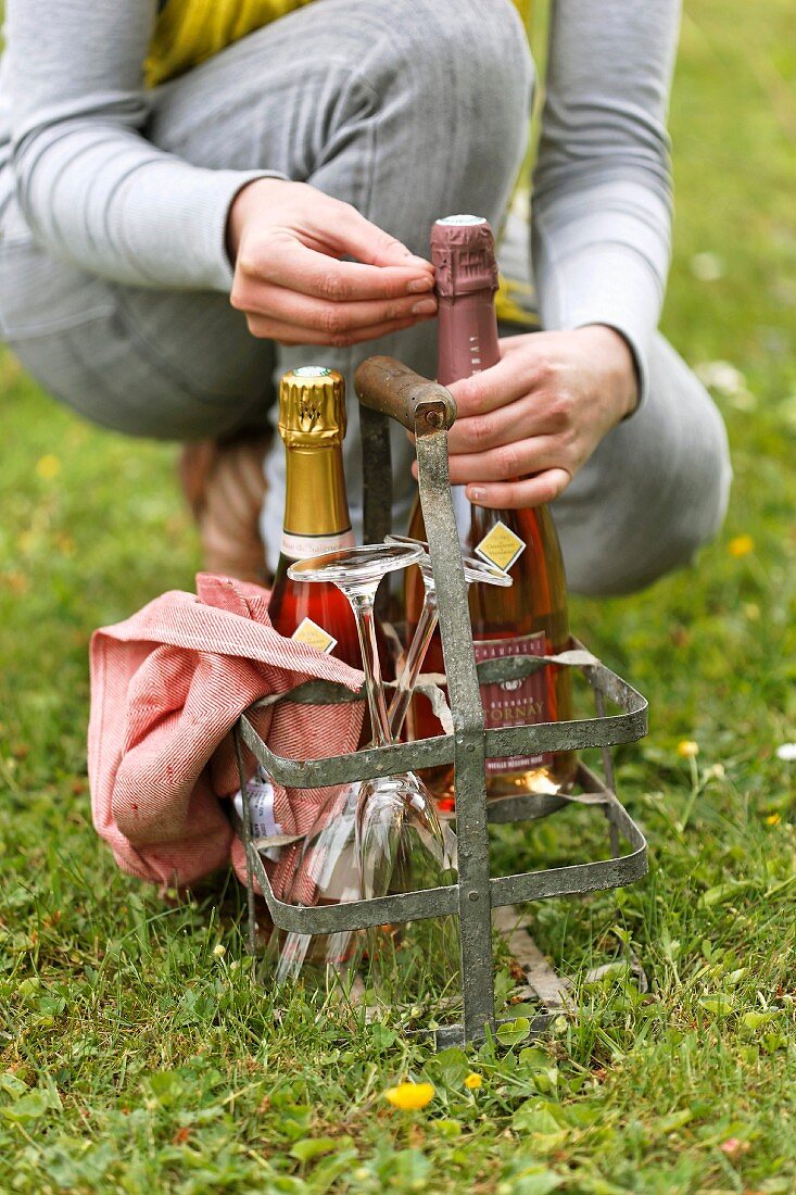 Person openning a bottle of Champagne in a metal bottle carrier