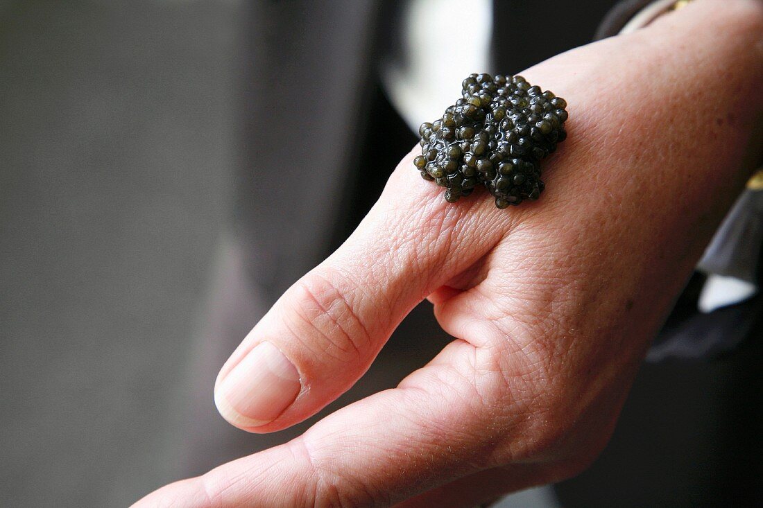 Placing a spoonful of caviar on a hand to taste