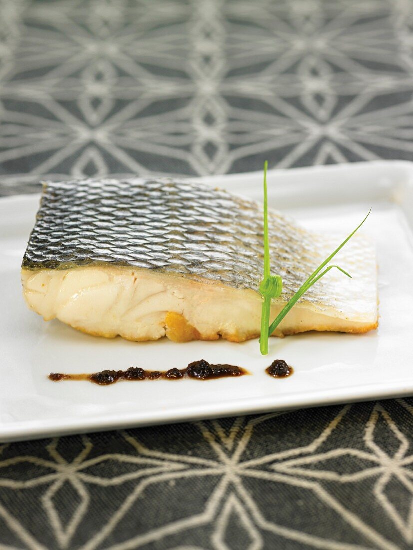 Oven-baked bass steak with black olive puree