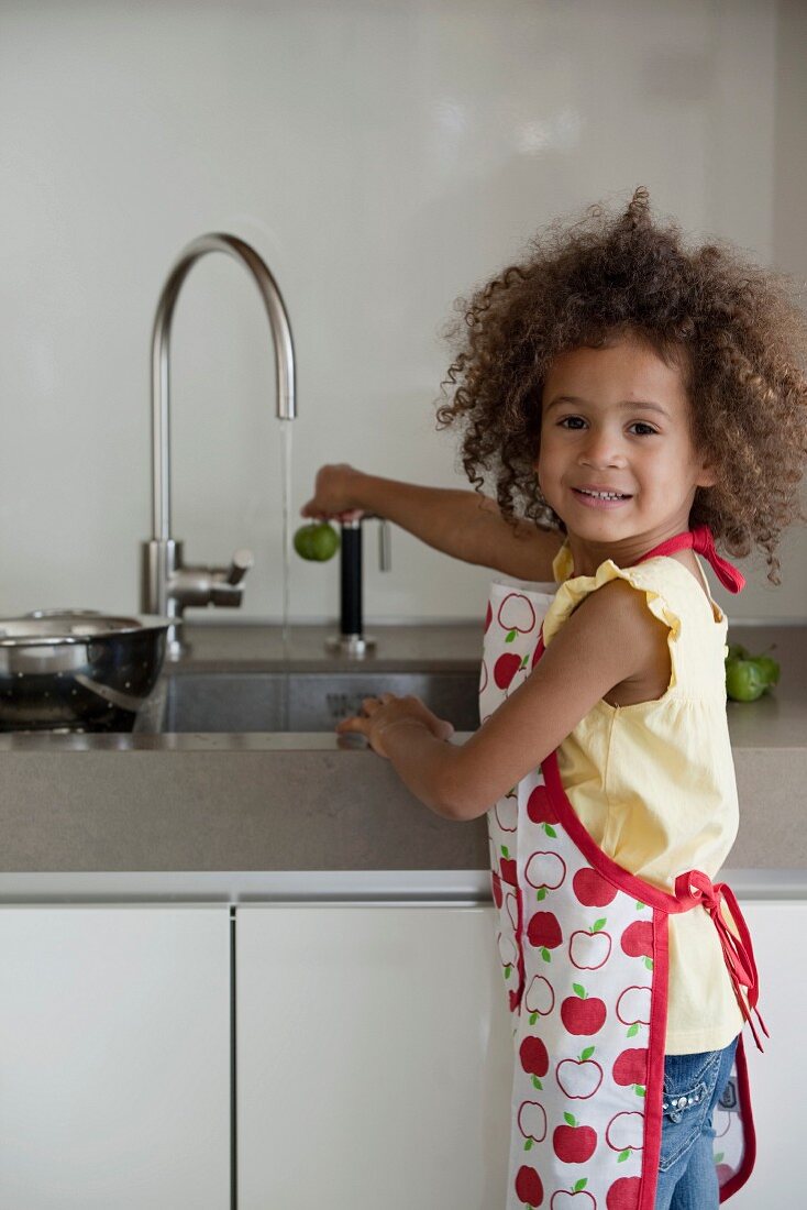 Young girl cleaning fruit under the tap water