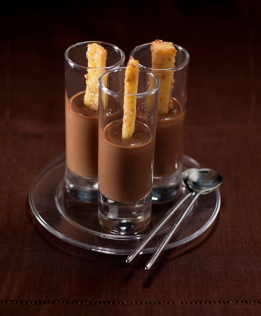 Karamell-Schokoladencreme serviert in Gläsern mit Sesamsticks