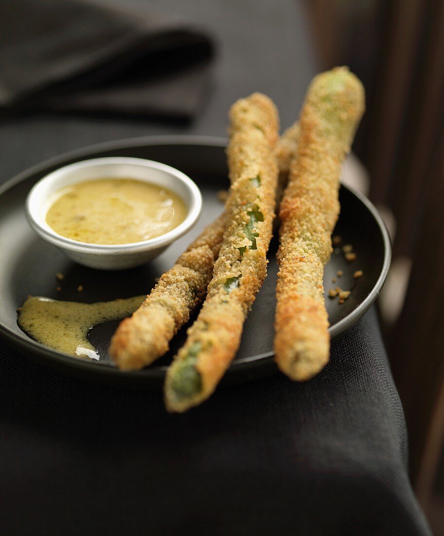 Fried asparagus coated in breadcrumbs with mustard sauce