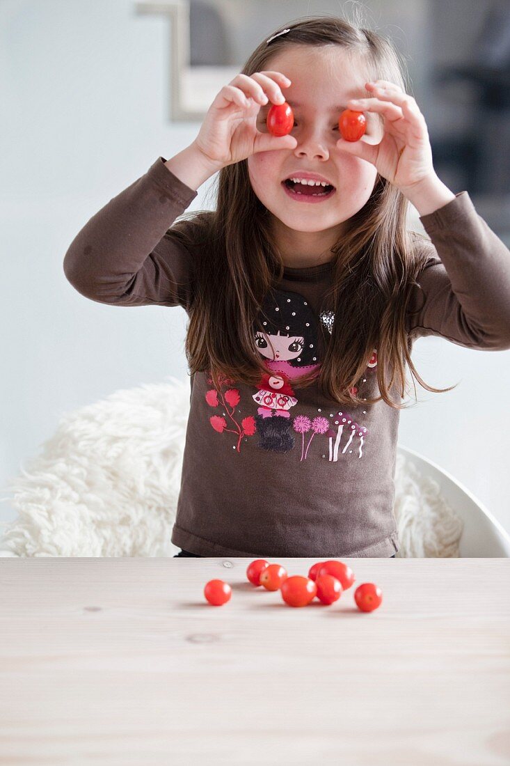 Kleines Mädchen spielt mit Kirschtomaten