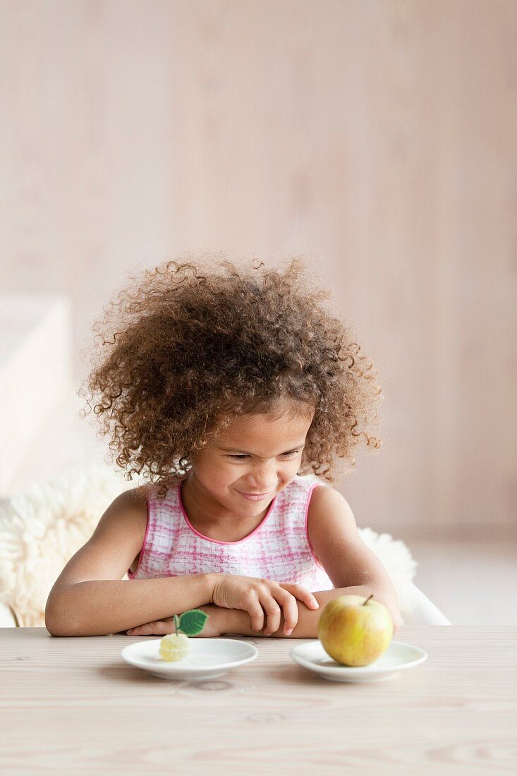 Kleines Mädchen schmollt vor einem Apfel