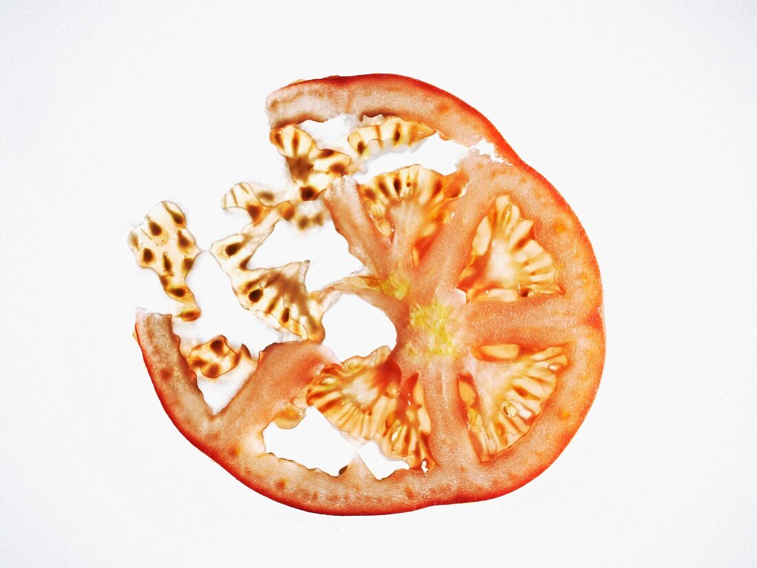 Hauchdünne Tomatenscheibe vor weißem Hintergrund