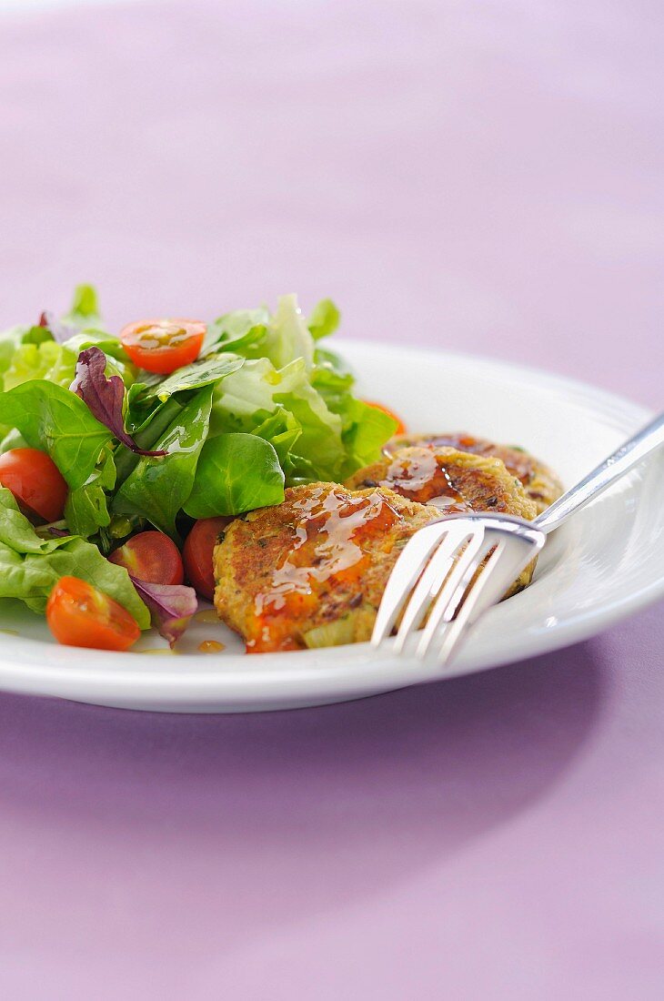 Small vegetable cakes with chili pepper sauce and mixed salad