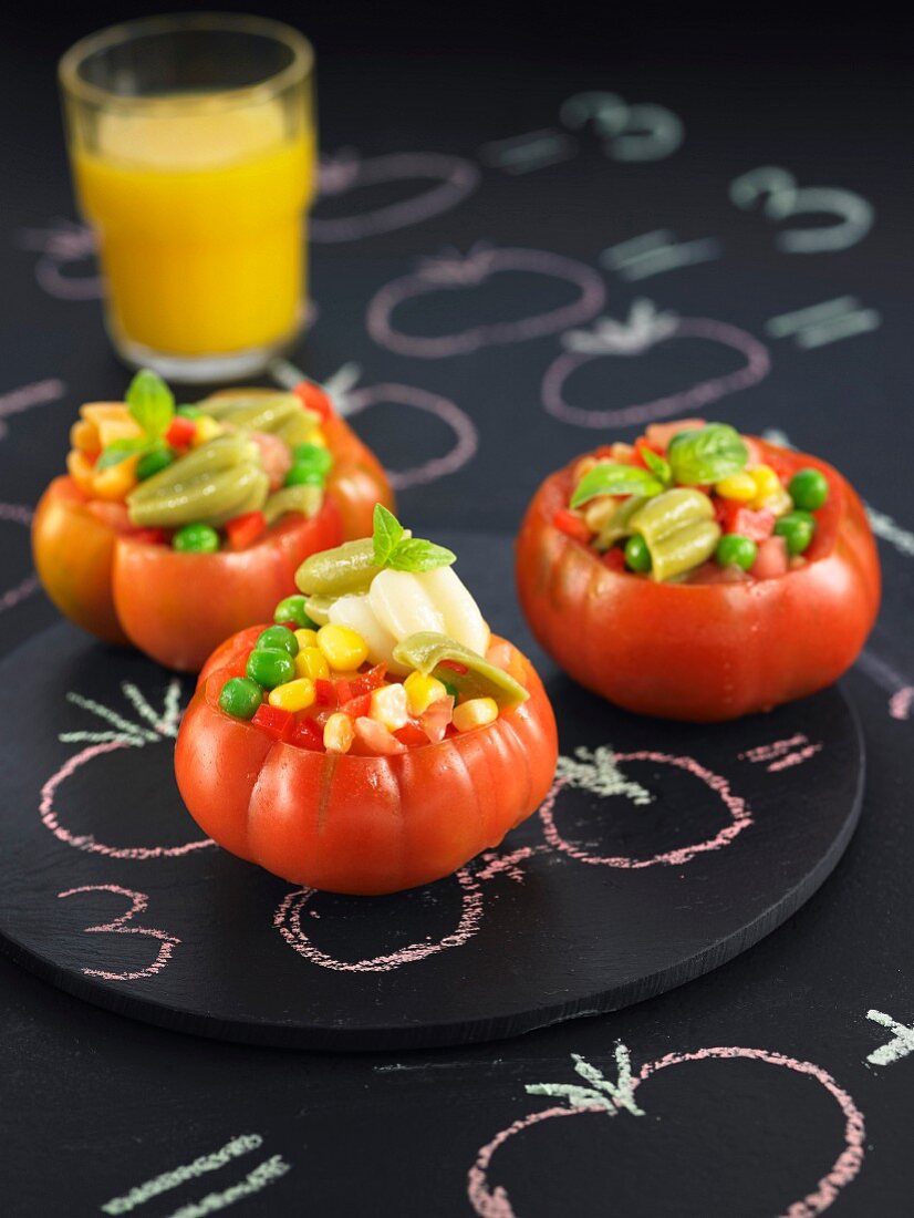 Raw tomatoes stuffed with peas, red peppers and sweet corn
