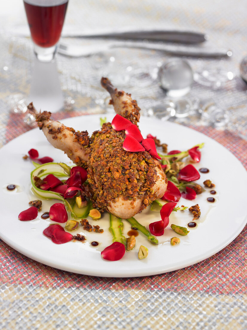 Quail coated in crushed pistachios with rose petals and green asparagus
