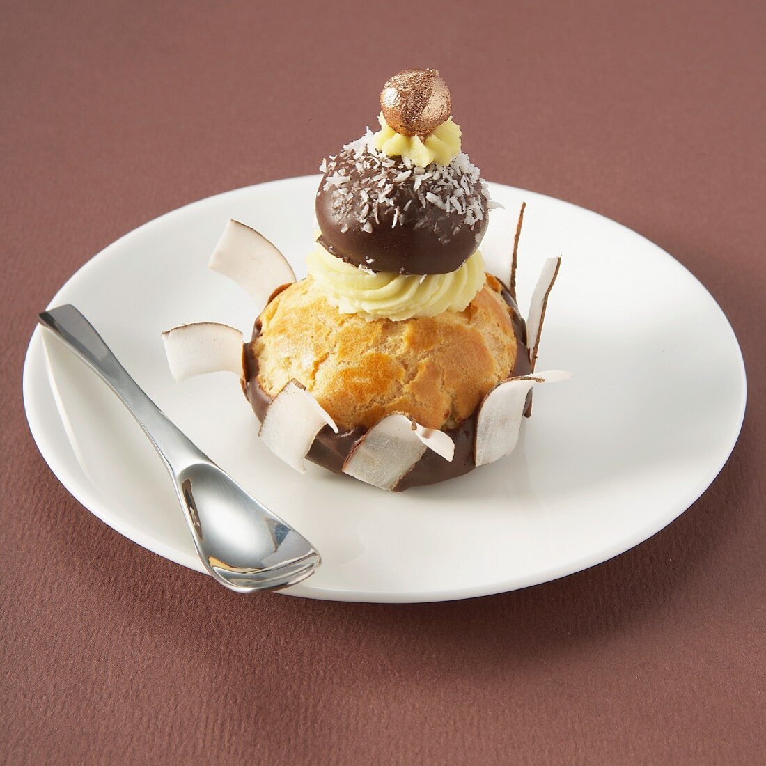 Religieuse (französisches Brandteigküchlein) mit Schokoglasur und Kokosraspeln