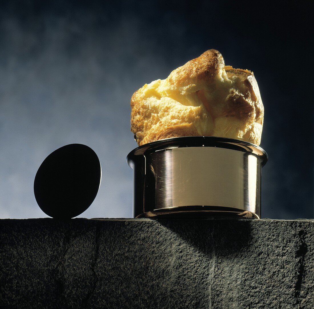 Popover-Brot in einem Topf auf Steinmauer, daneben ein Ei