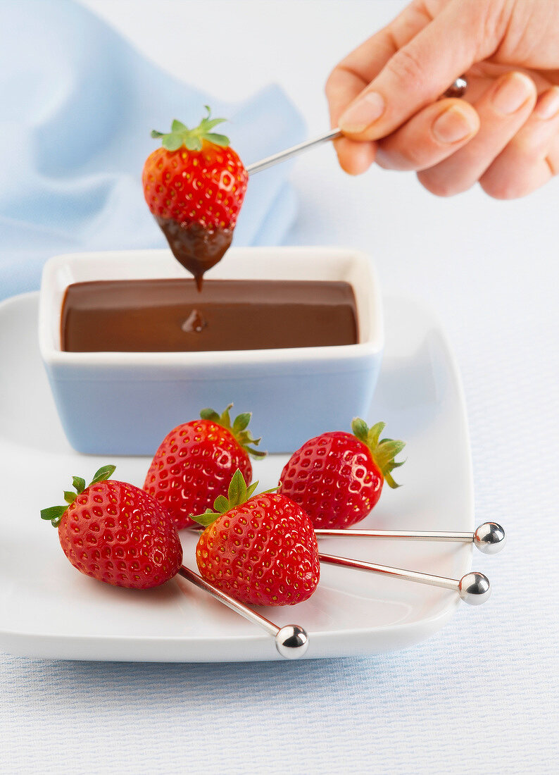 Dipping strawberries into melted chocolate