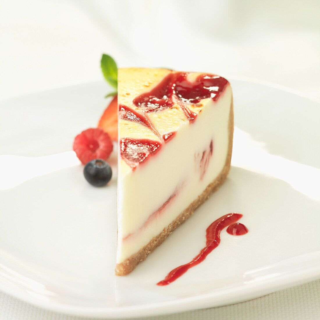 A slice of cheesecake with red berry coulis