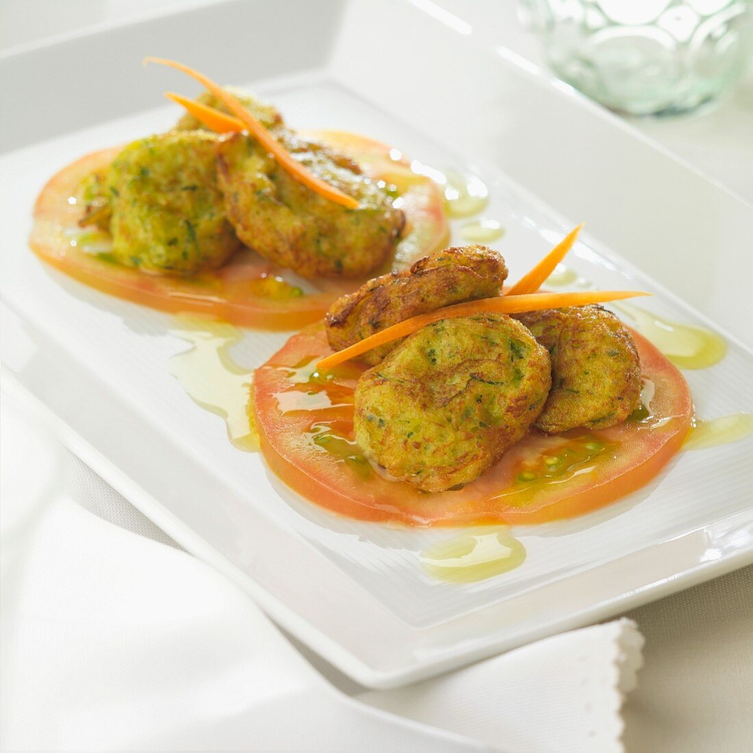 Zucchini croquettes on thinly sliced tomatoes
