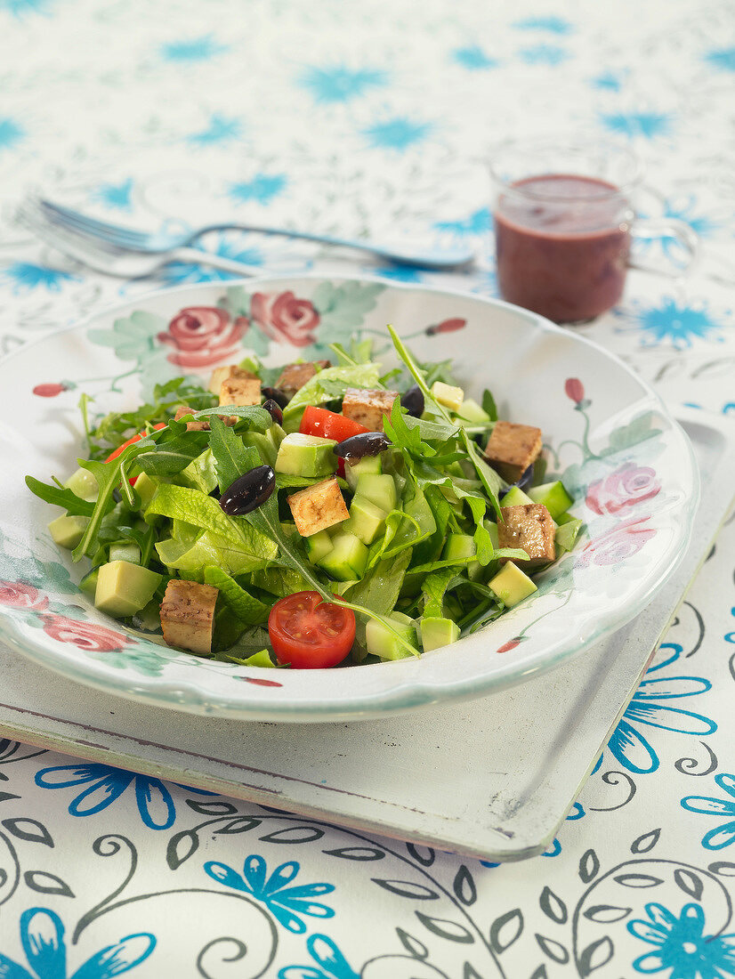 Salat mit Seitan, Tomaten, Avocado und Oliven serviert mit Rote-Bete-Sauce