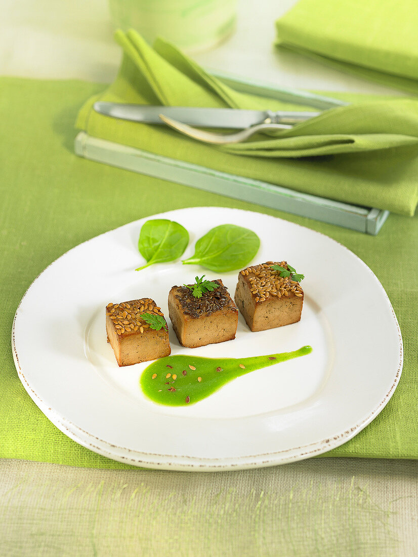 Tofu cubes coated with linseeds, pureed spinach sauce