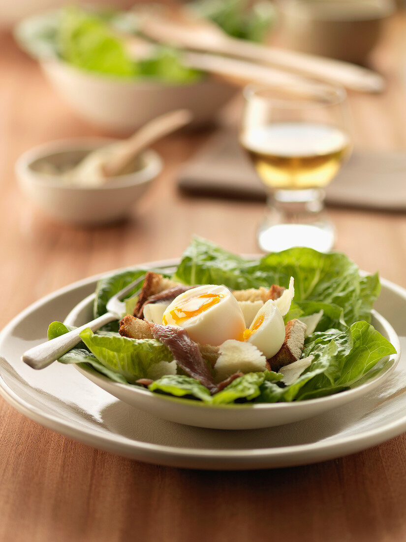 Spinach salad with soft-boiled egg, anchovies and roquefort on bread