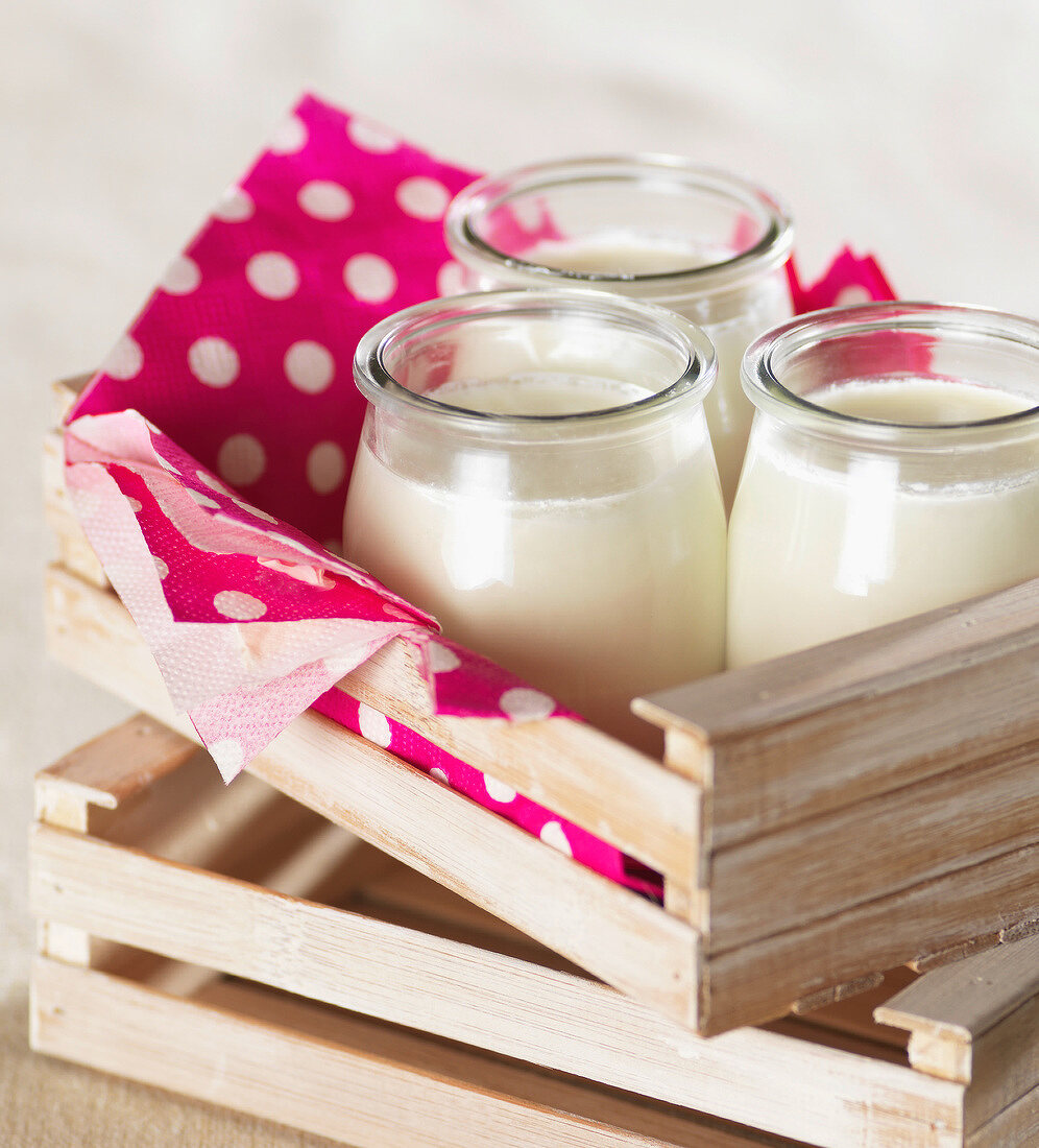 Holzkistchen mit Joghurt in drei Gläsern