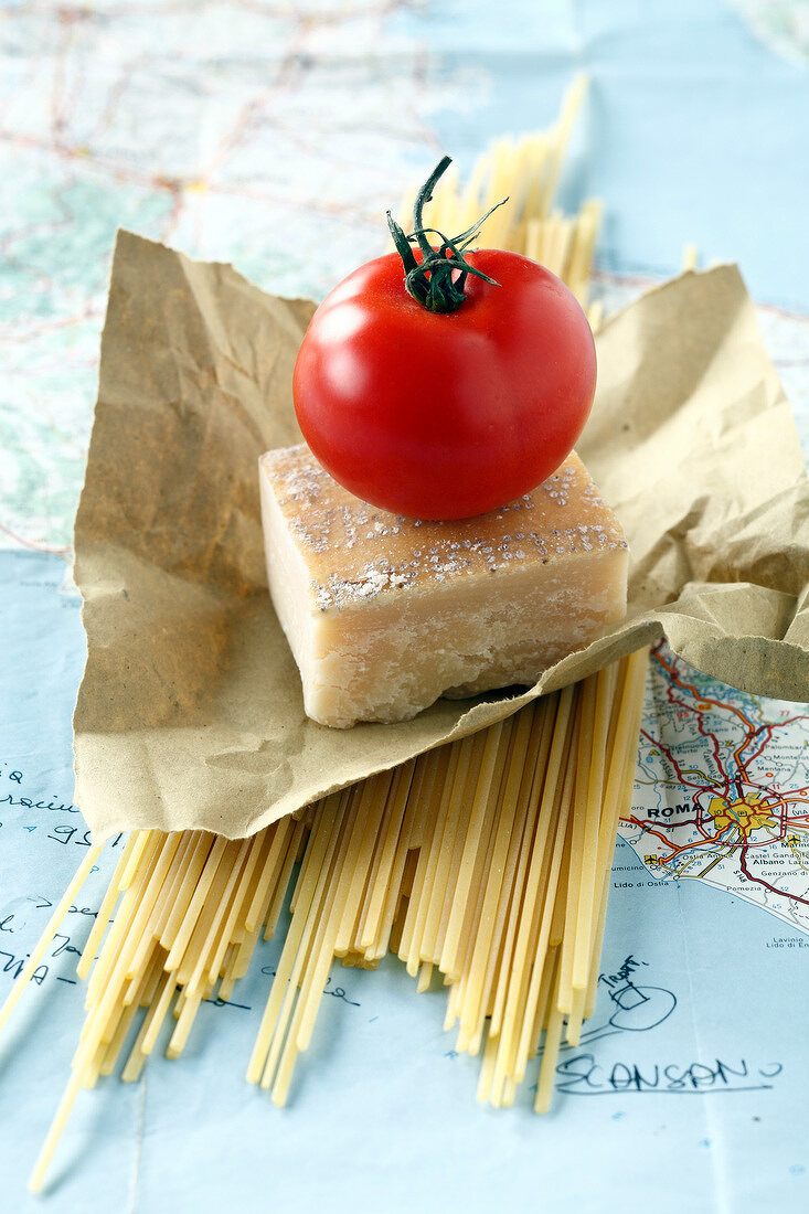 Spaghettis, parmesan and a tomato on a road map of Italy