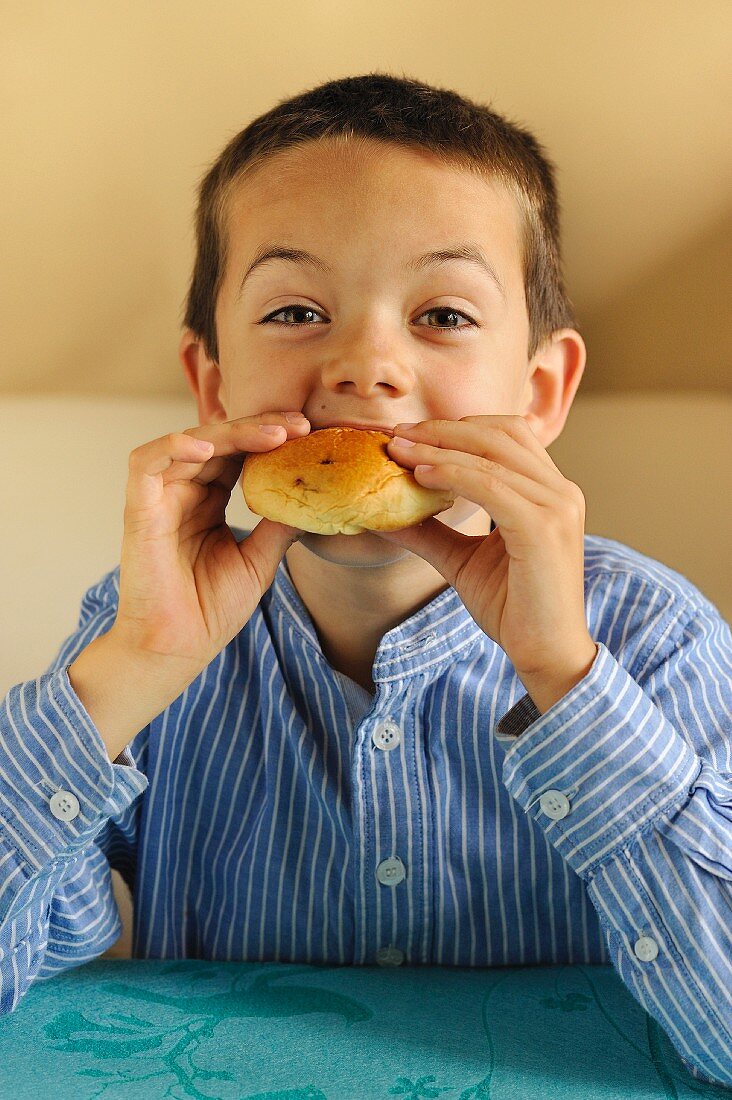 Young boy eating a bun