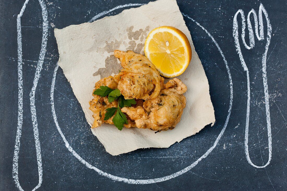 "Deep-fried battered fish ;Plate ,knife and fork drawn on the table"