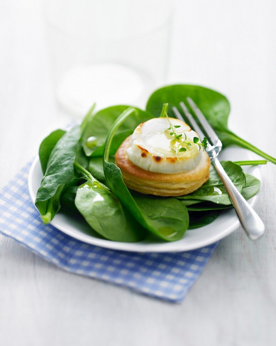 Goat's cheese and honey mini puff pastry tarlet with baby spinach leaves