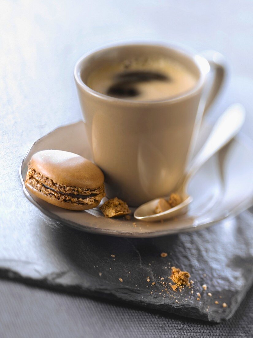 Eine Tasse Espresso mit Macaron daneben
