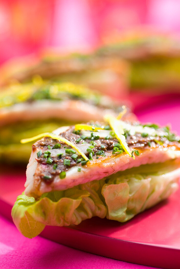 Rotbarbenfilets mit Tapenade serviert auf halbierten Salatherzen