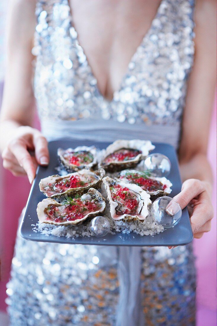 Elegant woman serving fresh oysters with raspberry vinaigrette