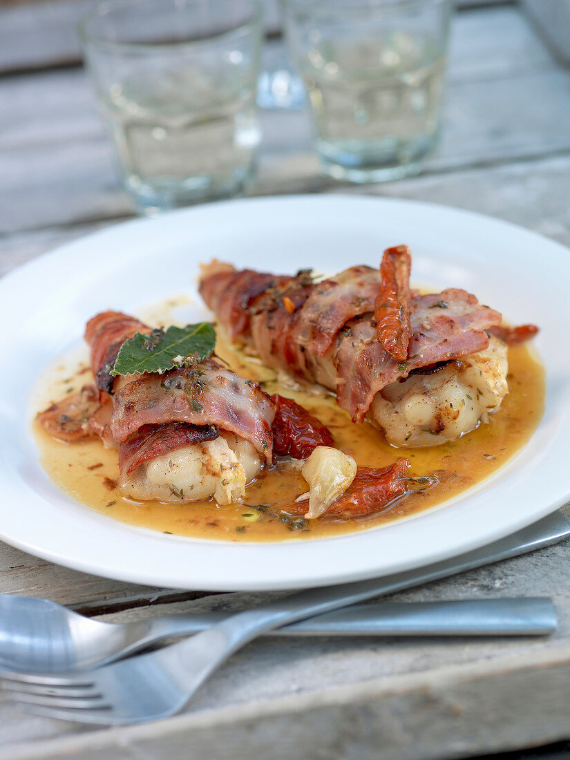 Fish fillets wrapped in bacon with sun-dried tomatoes