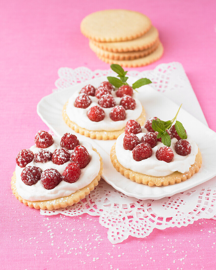 Mürbeteigplätzchen mit gesüßter Sahne und Himbeeren