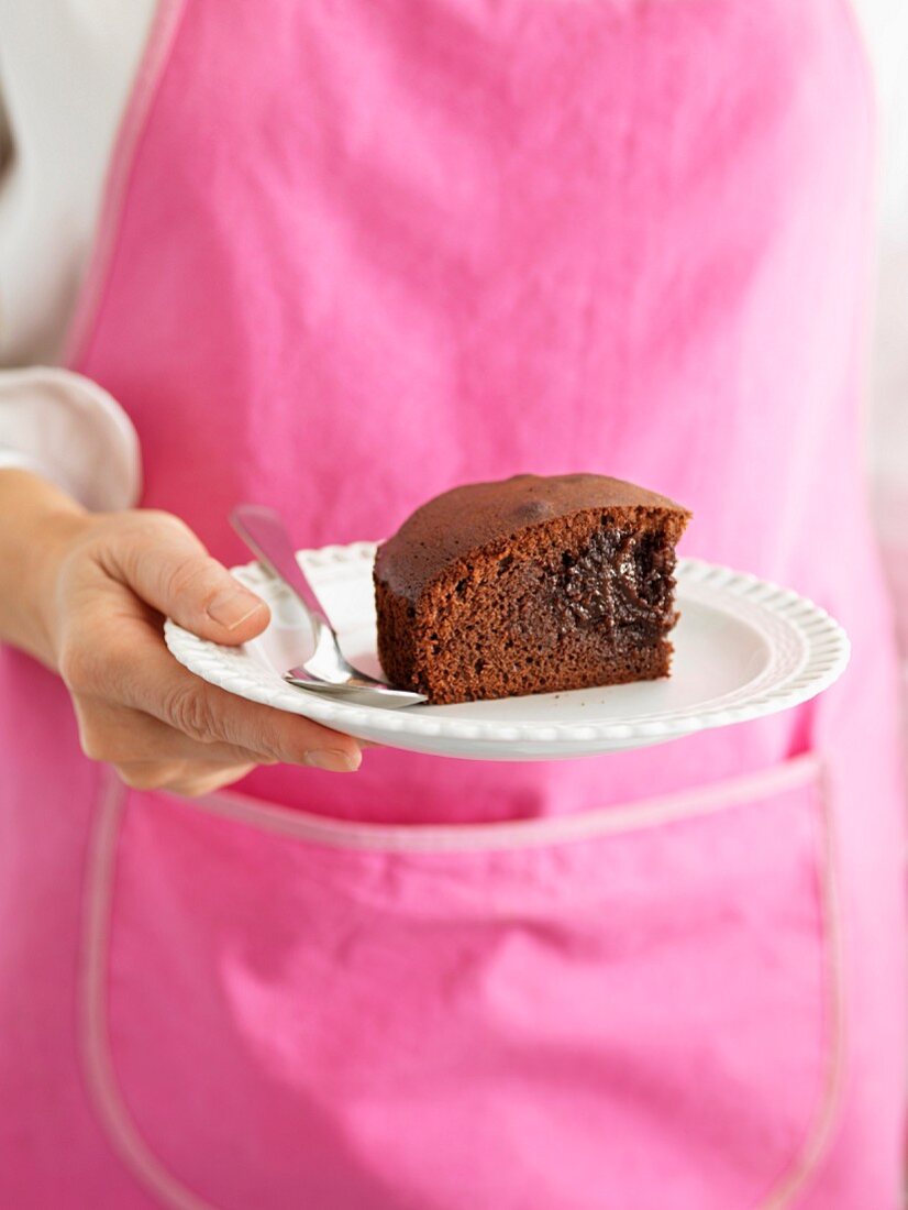 Person holding a plate of a portion of chocolate fondant