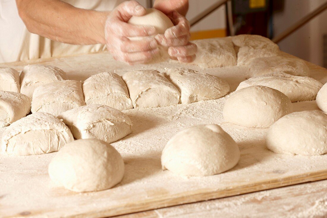 Woman using a dough cutter to divide the naan bread dough into six equal  portions which are flattened and baked. Bakers and pas Stock Photo - Alamy