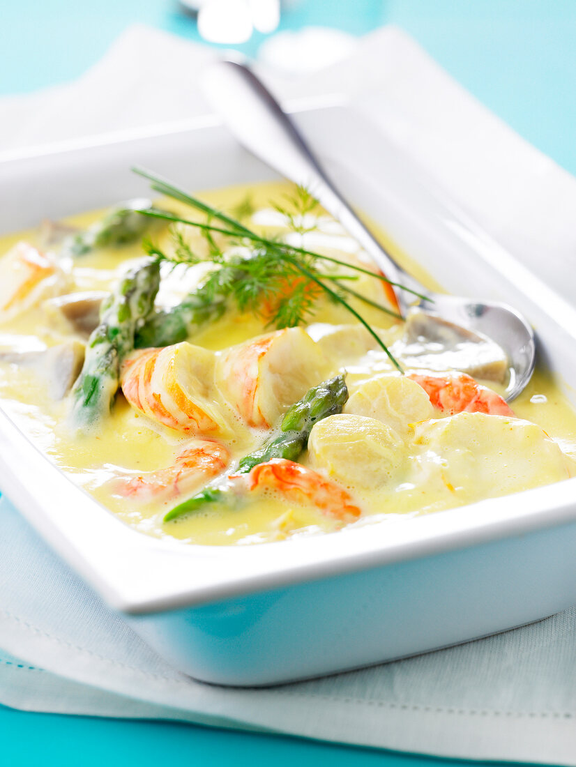 Sliced spiny lobster in creamy sauce with green asparagus