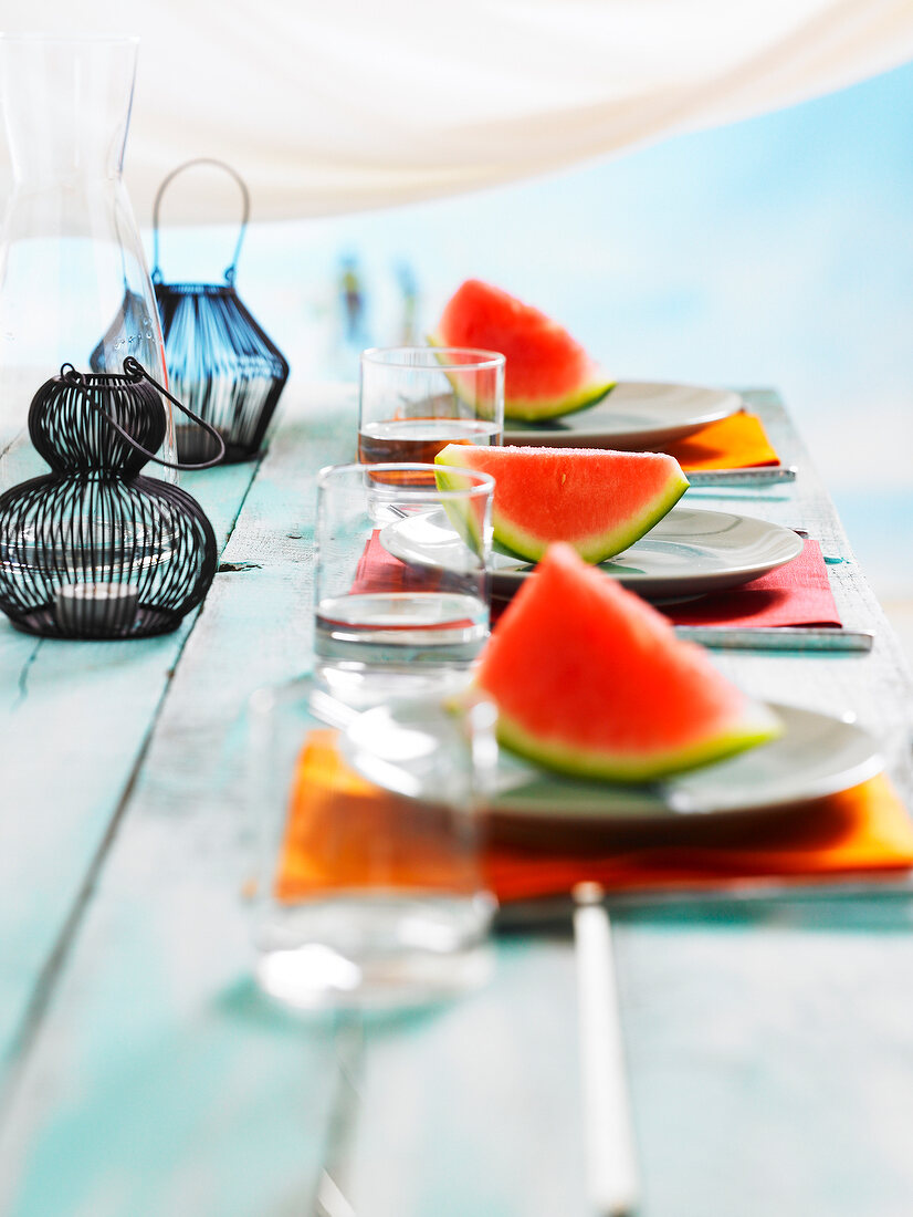 Gedeckter Tisch mit Wassermelonenscheiben und kleinen Laternen