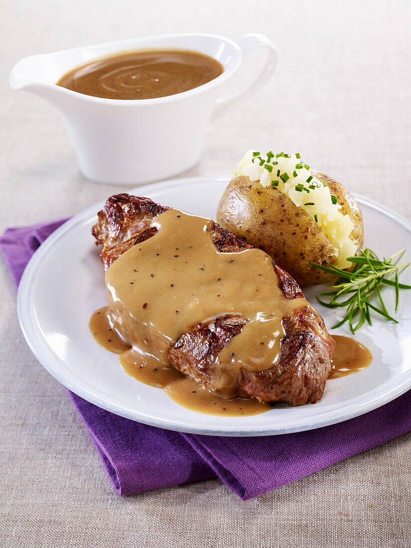 Beef flank steak with pepper sauce and a baked potato