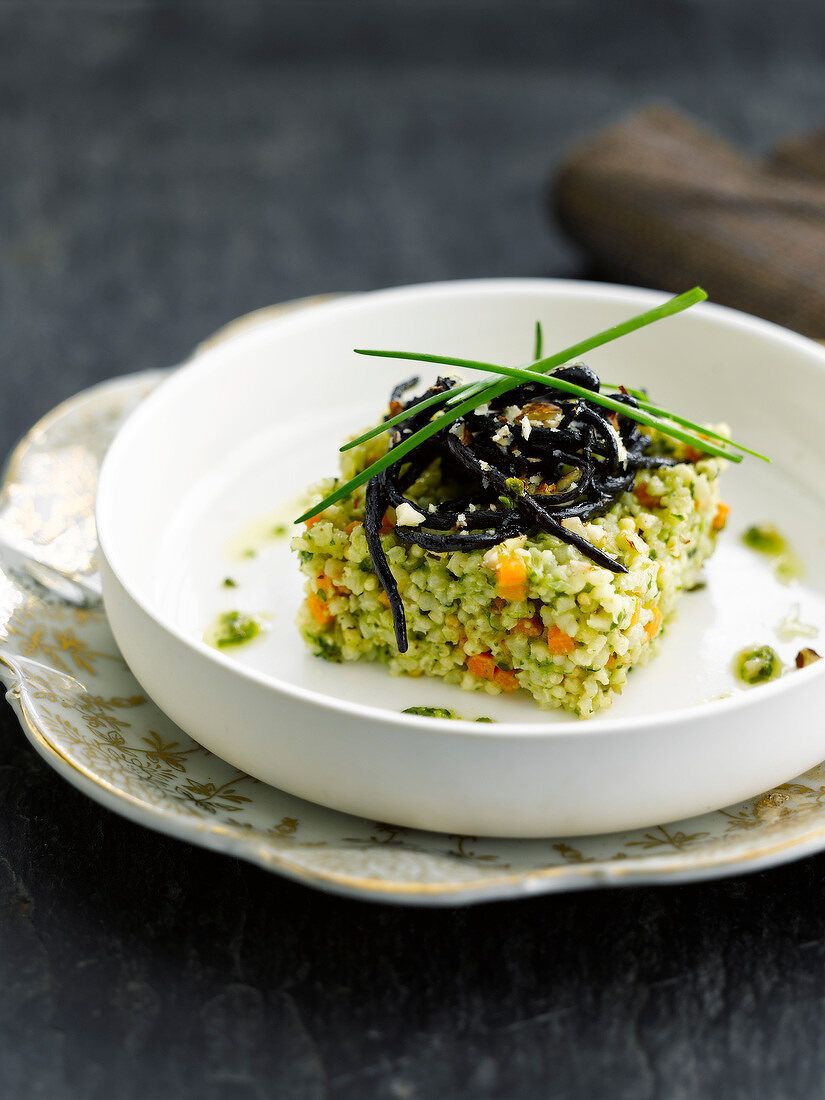 Millet with herbs and hazelnuts topped with squid ink spaghetti