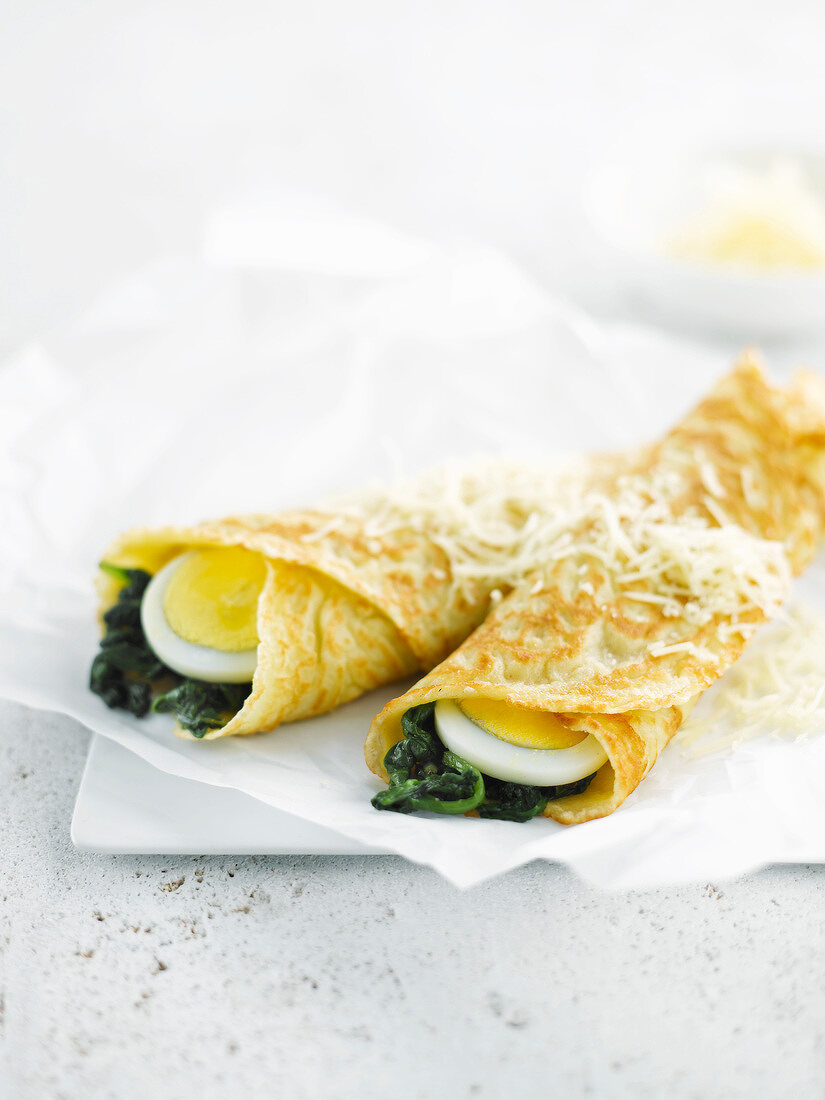 Rolled pancakes garnished with spinach and hard-boiled eggs