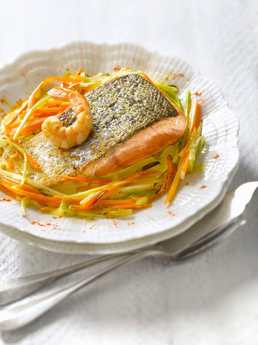 Saffron-flavored piece of salmon with shrimps and thinly sliced vegetables