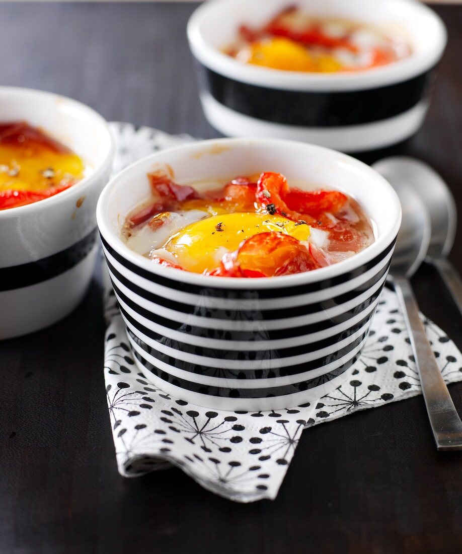 Small casserole dishes of coodled egg with red peppers and pata negra ham