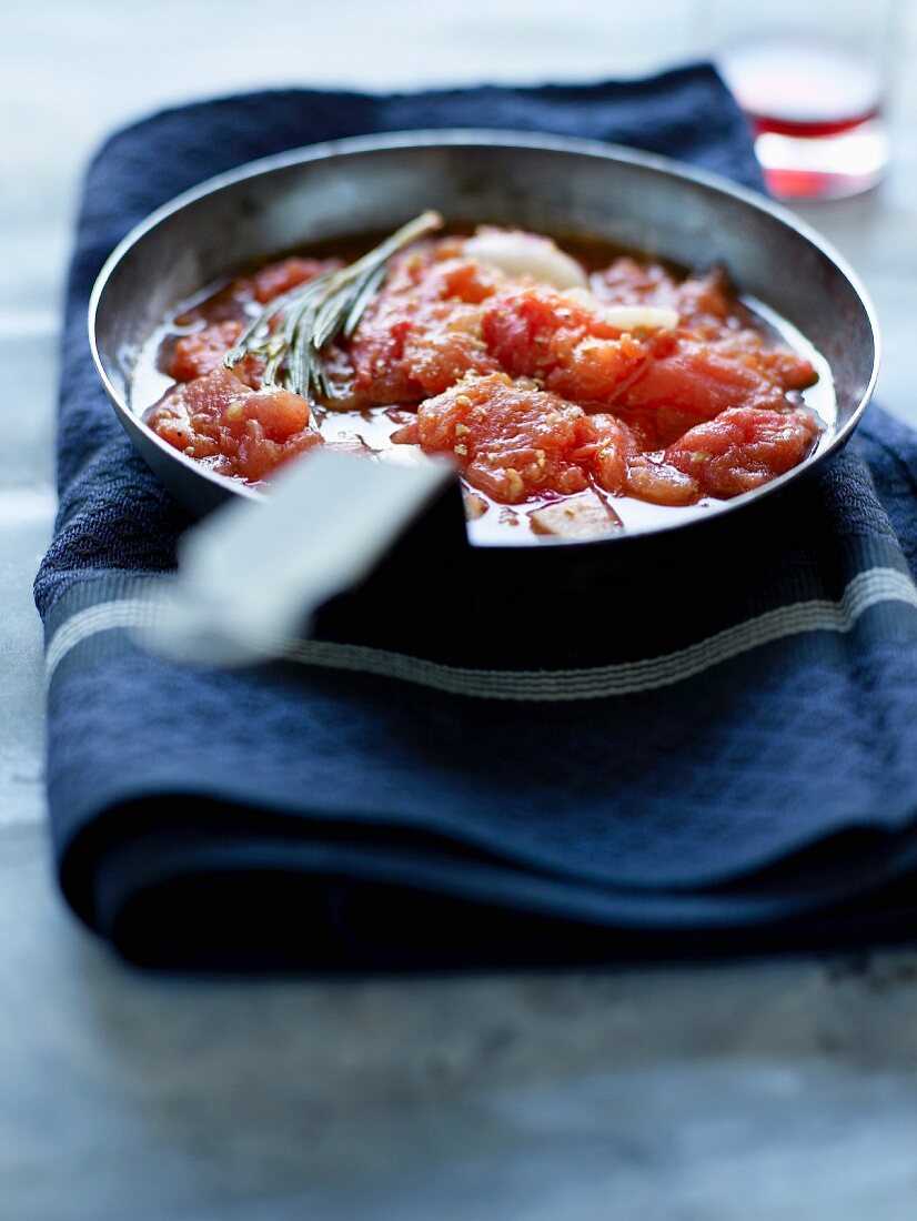 Tomatensauce in einer Pfanne, Weinflasche im Hintergrund