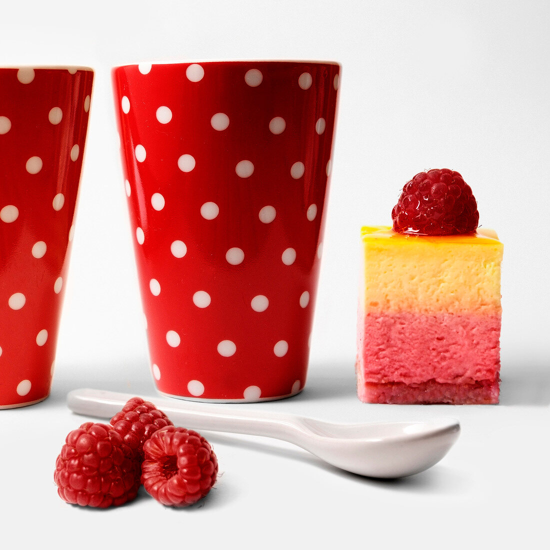 Piece of raspberry cake and two spotted cups