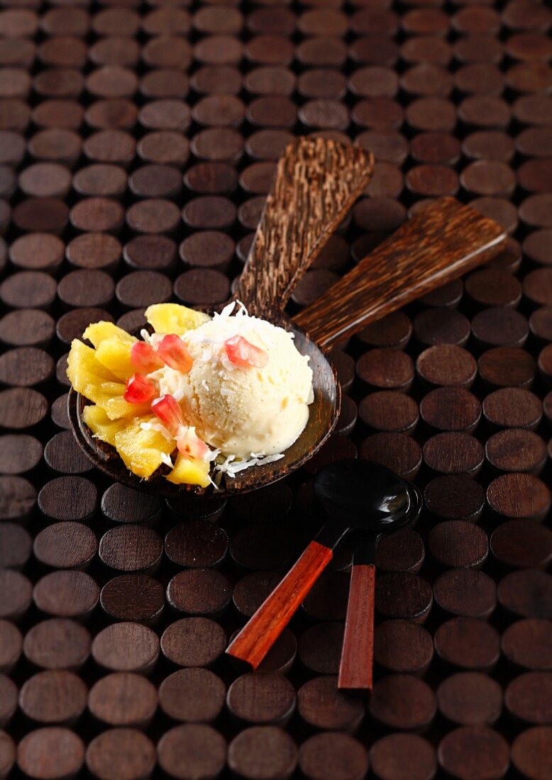 A scoop of coconut ice cream with pineapple and pomegranate carpaccio
