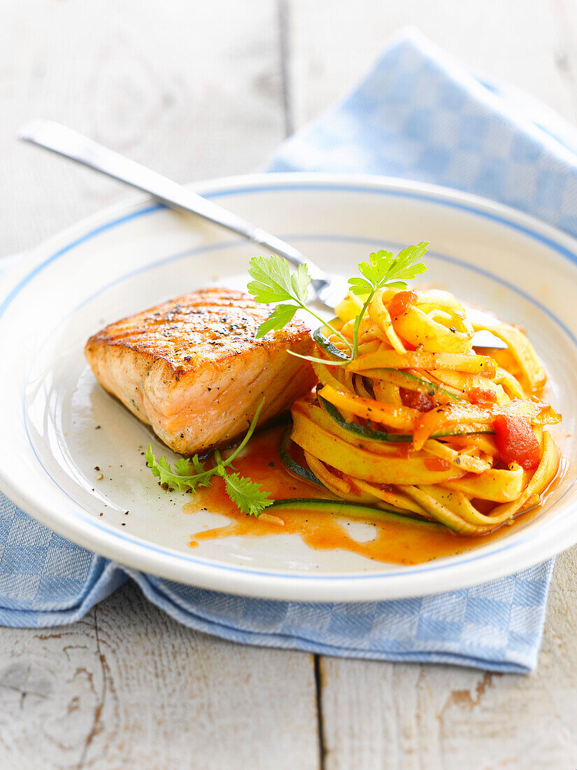 Thick piece of grilled salmon,tagliatelles in tomato sauce with thin strips of zucchinis